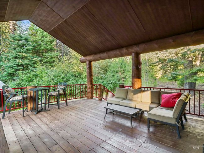 Wooden terrace featuring an outdoor hangout area and a wooded view | Image 47
