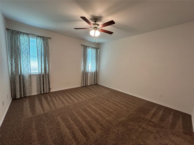Unfurnished room with plenty of natural light, ceiling fan, dark carpet, and baseboards | Image 22