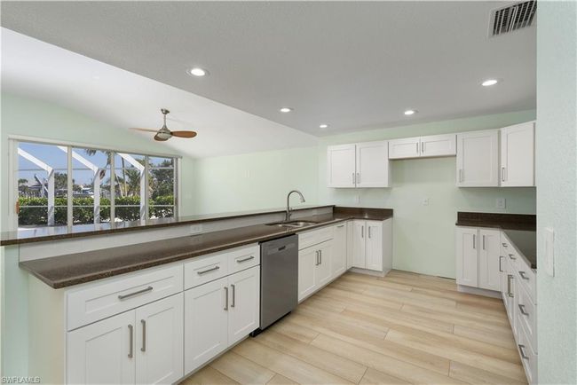 Kitchen with stainless steel dishwasher, white cabinets, a sink, visible vents, and a ceiling fan | Image 6