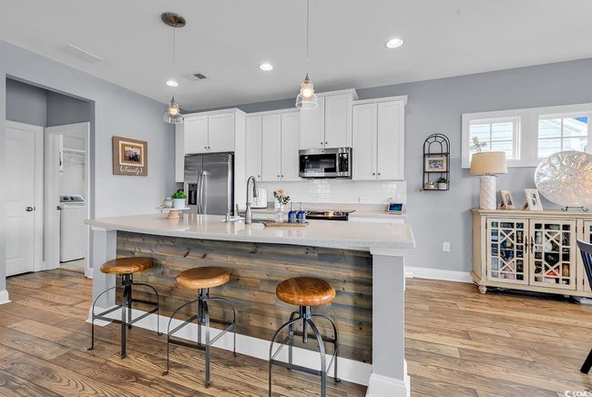 Open kitchen with large island, stainless appliances and tiled backsplash. | Image 5