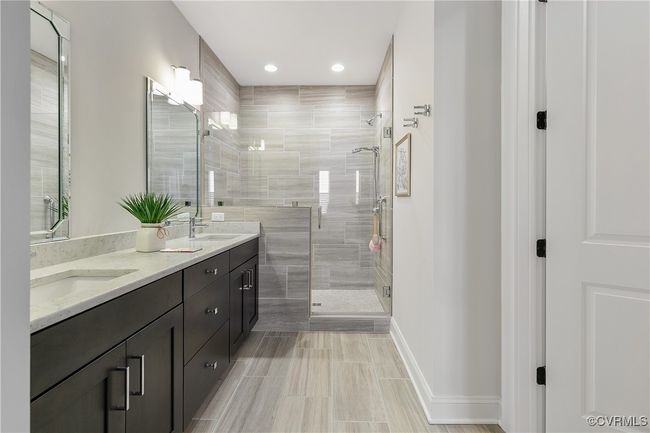 Full bathroom featuring double vanity, a shower stall, baseboards, and a sink | Image 24