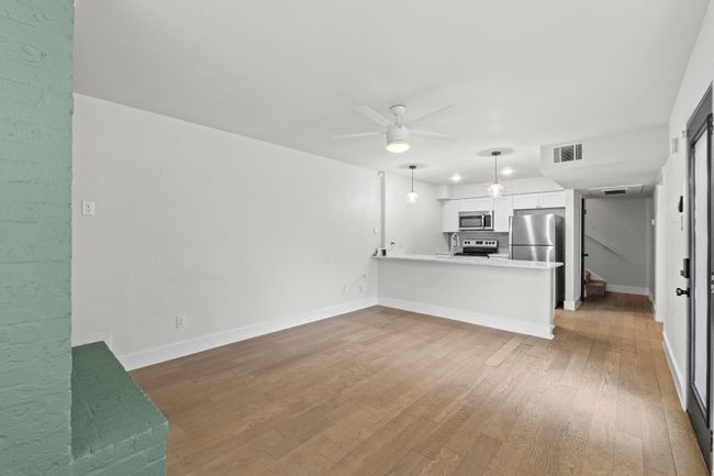 Unfurnished living room with ceiling fan, wood finished floors, and baseboards | Image 9
