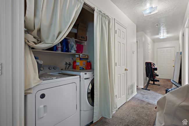 Laundry area featuring washing machine and dryer, carpet, and a textured ceiling | Image 44