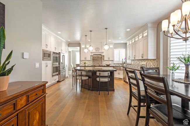 Kitchen featuring stainless steel appliances, a chandelier, light wood-style flooring, decorative backsplash, and recessed lighting | Image 15