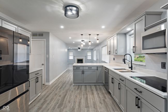 kitchen featuring gray cabinets, stainless steel appliances, a sink, ceiling fan, and light wood finished floors | Image 11