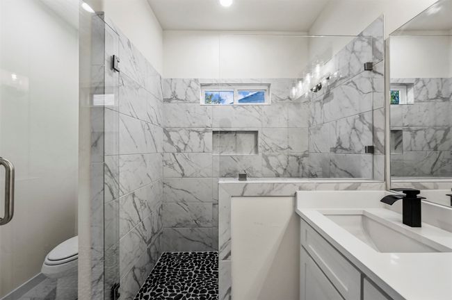 Full bathroom with toilet, marble finish floor, tiled shower, and vanity | Image 22