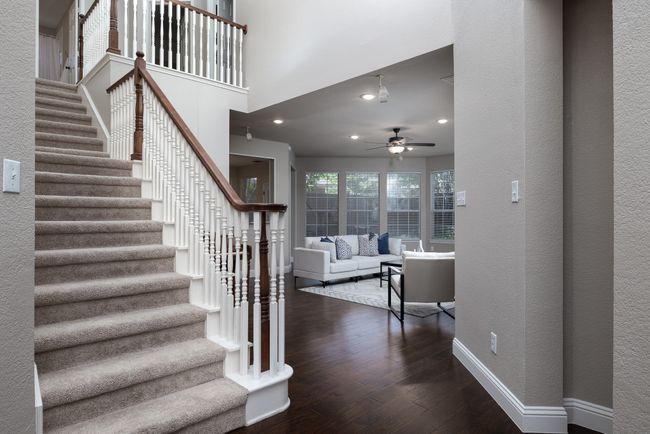 Staircase featuring a ceiling fan, wood finished floors, a textured wall, and recessed lighting | Image 11