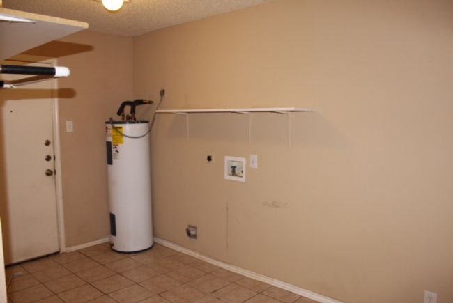 Washroom with electric water heater, electric dryer hookup, washer hookup, light tile patterned flooring, and a textured ceiling | Image 6