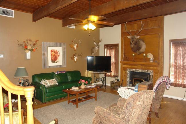 Living room featuring hardwood / wood-style floors, a fireplace, ceiling fan, wooden ceiling, and beam ceiling | Image 4