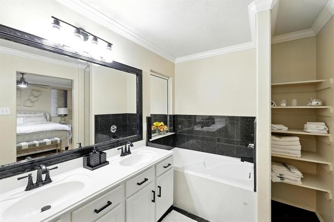 Relax in the deep soaking tub surrounded by sleek black tile. Built-in shelving and extended counter space provide stylish functionality. | Image 17