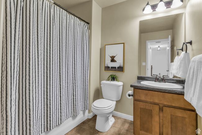 Bathroom with tile patterned floors, vanity, baseboards, shower / tub combo, and toilet | Image 18