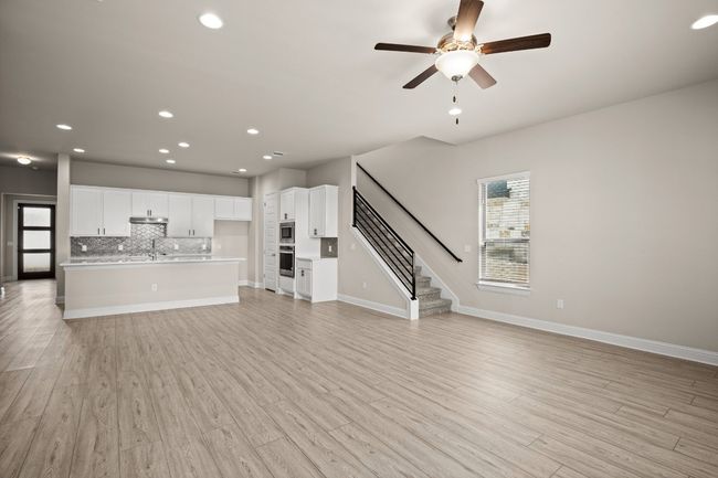 Unfurnished living room featuring recessed lighting, baseboards, ceiling fan, light wood-style floors, and stairway | Image 8