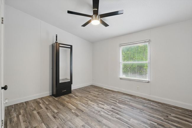 Spare room featuring vaulted ceiling, a ceiling fan, wood finished floors, and baseboards | Image 16
