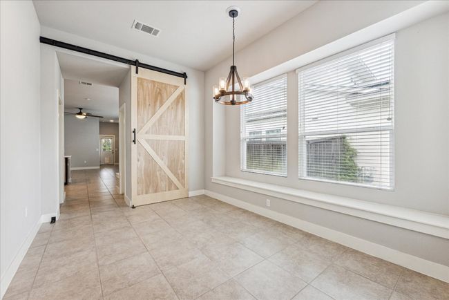 Unfurnished dining area with a barn door, a chandelier, baseboards, ceiling fan, and light tile patterned flooring | Image 20