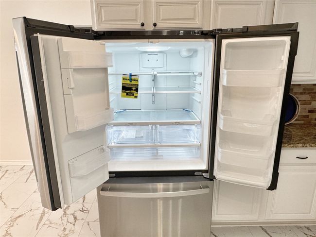 Kitchen view of white cabinetry, dark stone countertops, and fridge | Image 14