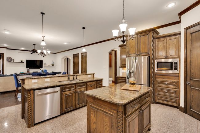Kitchen with a sink, island, exceptional cabinetry, double pantries, stainless steel appliances, and ornamental molding | Image 13
