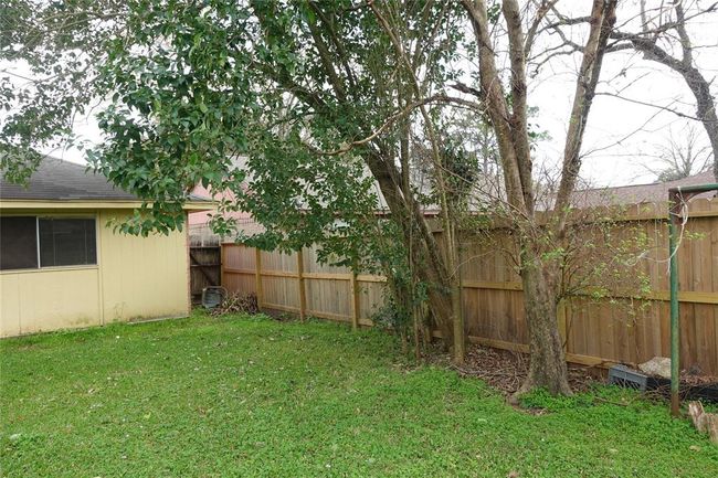 Charming side yard with lush greenery and a sturdy fence, perfect for privacy and relaxation. | Image 28