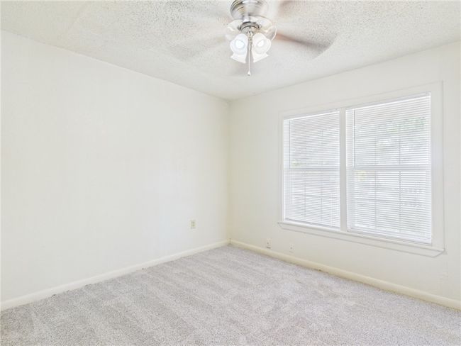 Empty room featuring light colored carpet, ceiling fan, and a textured ceiling | Image 17
