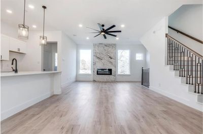 Unfurnished living room with light wood-type flooring, ceiling fan, a high end fireplace, and plenty of natural light | Image 1