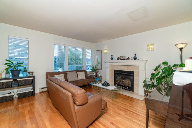 Living area with a baseboard radiator, light wood-style flooring, and a tiled fireplace | Image 7
