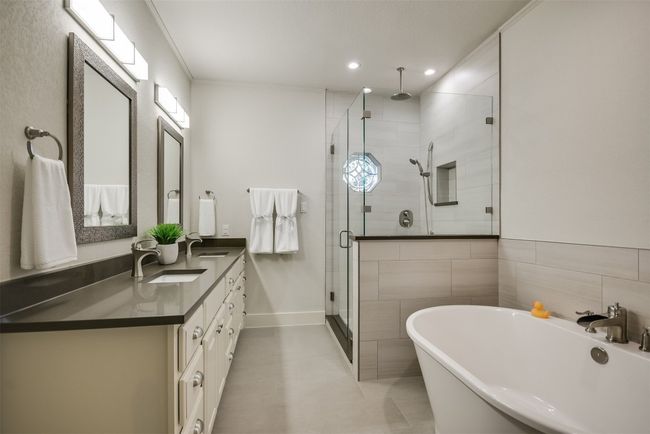 An elegant en-suite bathroom in the primary bedroom boasts a soaking tub and a separate glass-enclosed shower | Image 12
