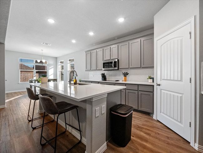 Kitchen with light countertops, a kitchen island with sink, stainless steel microwave, and a sink | Image 5