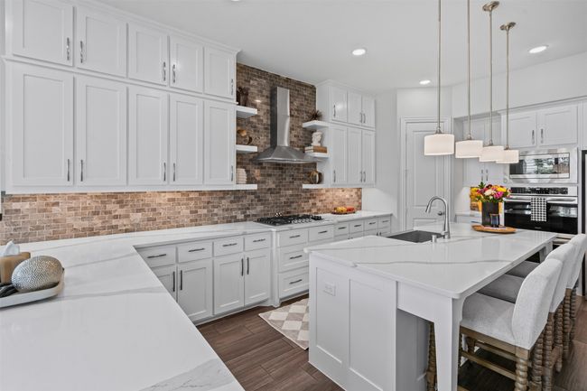 Kitchen featuring appliances with stainless steel finishes, a sink, wall chimney exhaust hood, backsplash, and white cabinetry | Image 18
