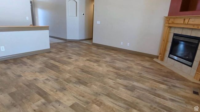 Unfurnished living room featuring wood finished floors, a tiled fireplace, and baseboards | Image 21