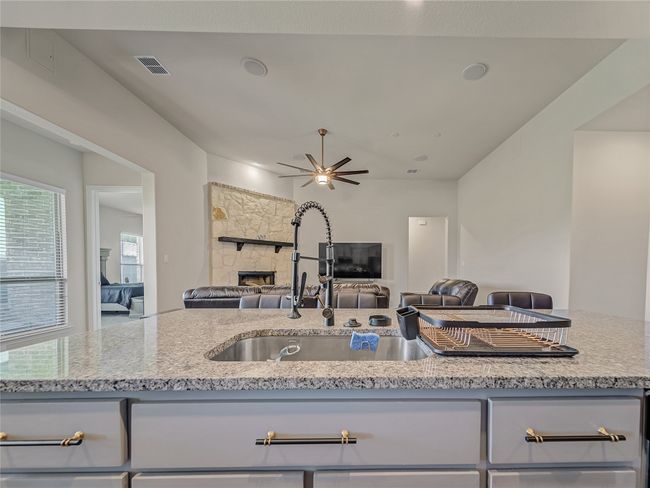 Kitchen featuring light stone countertops, open floor plan, gray cabinetry, and a ceiling fan | Image 14