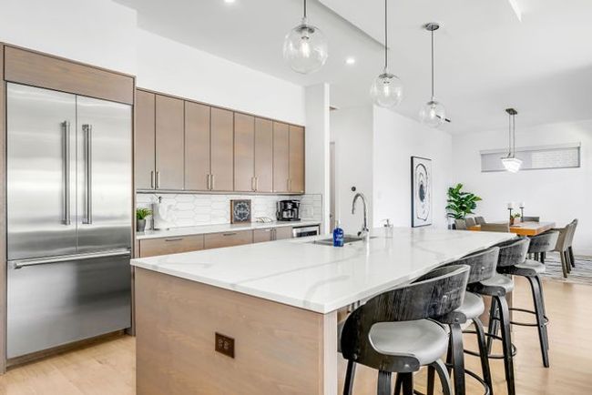 Kitchen featuring built in fridge, hanging light fixtures, a kitchen island with sink, and sink | Image 12