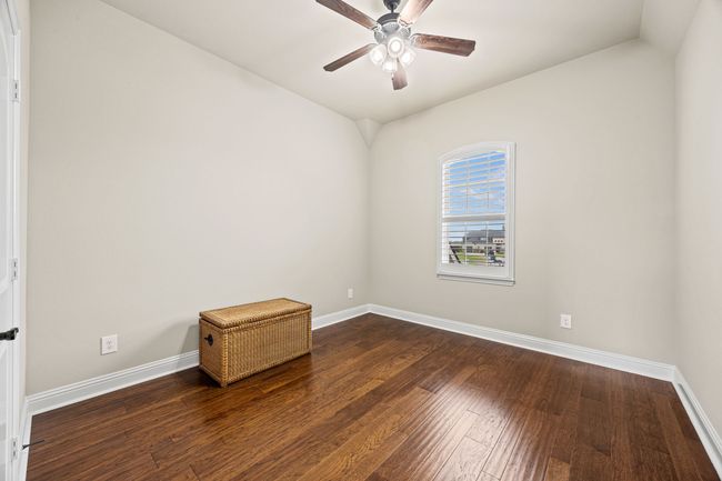 Empty room with baseboards, wood flooring, lofted ceiling, and ceiling fan | Image 8