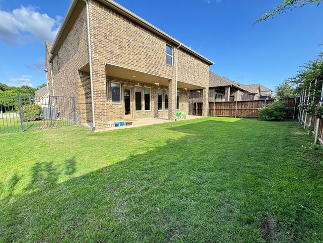 Rear view of house featuring brick siding, a fenced backyard, and a patio area | Image 29