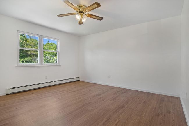 Unfurnished room with a baseboard heating unit, wood finished floors, baseboards, and a ceiling fan | Image 21
