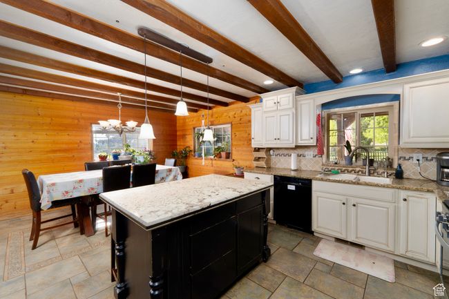 Kitchen with black dishwasher, a sink, wood walls, tasteful backsplash, and a chandelier | Image 14