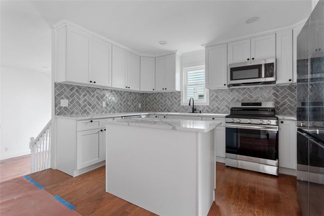 Kitchen with stainless steel appliances, dark wood-style flooring, decorative backsplash, and a sink | Image 4