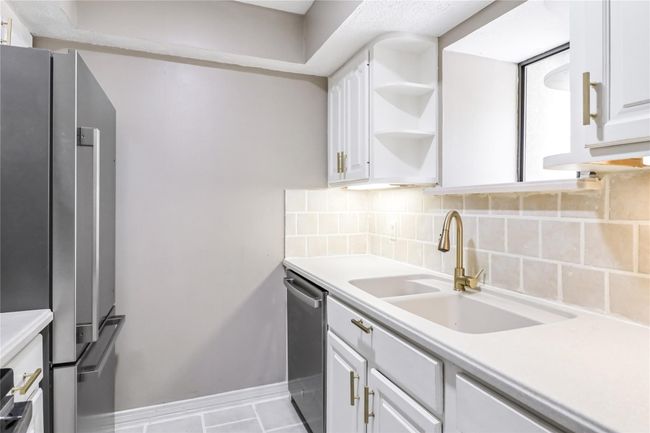 Kitchen with a sink, decorative backsplash, white cabinets, and light countertops | Image 14
