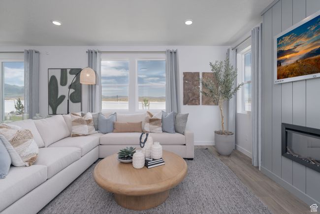 Living room featuring light wood finished floors, a fireplace, and recessed lighting | Image 28