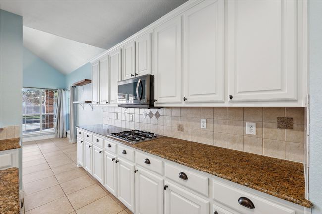 Kitchen featuring vaulted ceiling, stainless steel appliances, white cabinetry, and dark stone countertops | Image 16