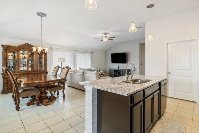 Kitchen with lofted ceiling, ceiling fan with notable chandelier, stainless steel dishwasher, a sink, and light tile patterned flooring | Image 14