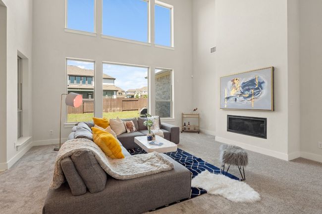 Carpeted living area with a glass covered fireplace, a high ceiling, and baseboards | Image 7