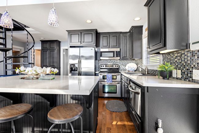 Kitchen with stainless steel appliances, light counter tops and generous island. | Image 4