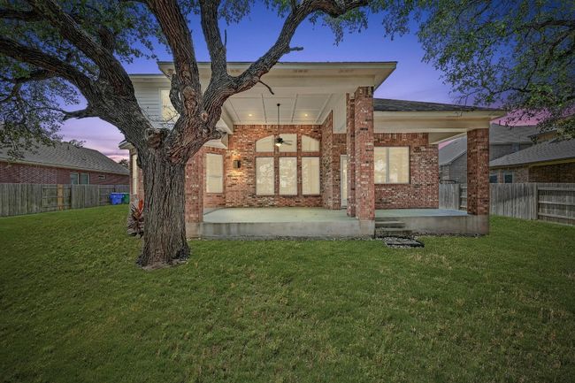 Back of property at dusk with brick siding, ceiling fan, and a fenced backyard | Image 38