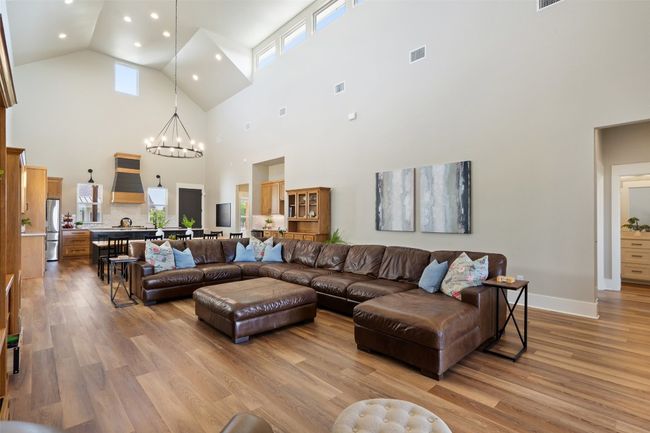 Living area featuring high vaulted ceiling, a chandelier, light wood-type flooring, recessed lighting, and healthy amount of natural light | Image 4