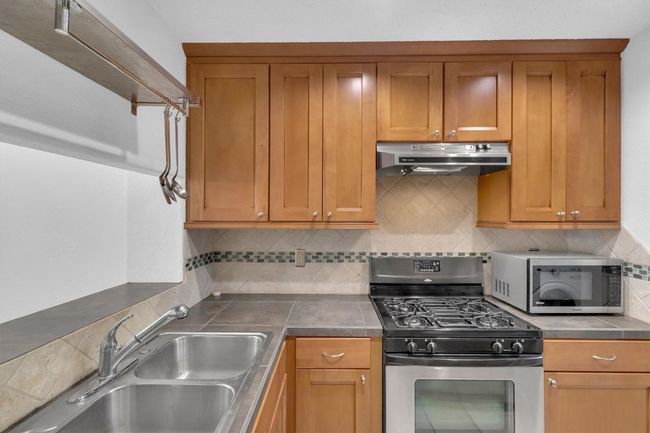 Kitchen with backsplash, a sink, stainless steel appliances, and under cabinet range hood | Image 6