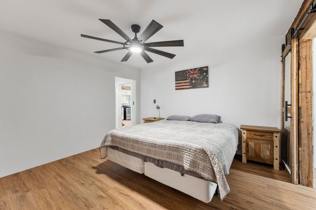 Bedroom with a barn door, a ceiling fan, and wood finished floors | Image 15