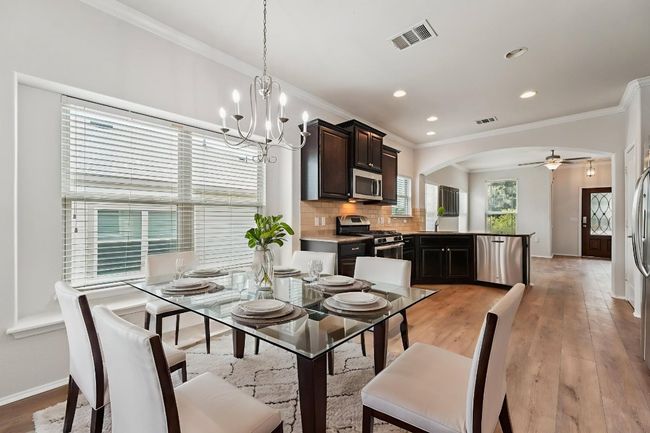 Dining area featuring ornamental molding, baseboards, arched walkways, a ceiling fan, and a chandelier | Image 16