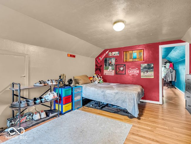 bedroom featuring a textured ceiling, wood finished floors, vaulted ceiling, and baseboards | Image 18