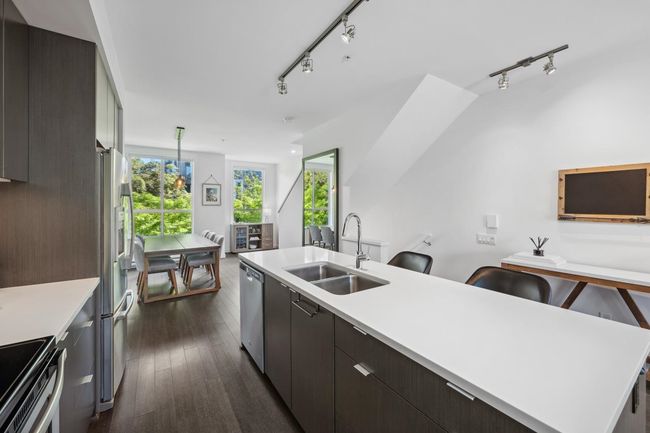 Kitchen featuring a sink, appliances with stainless steel finishes, track lighting, light countertops, and dark wood finished floors | Image 11