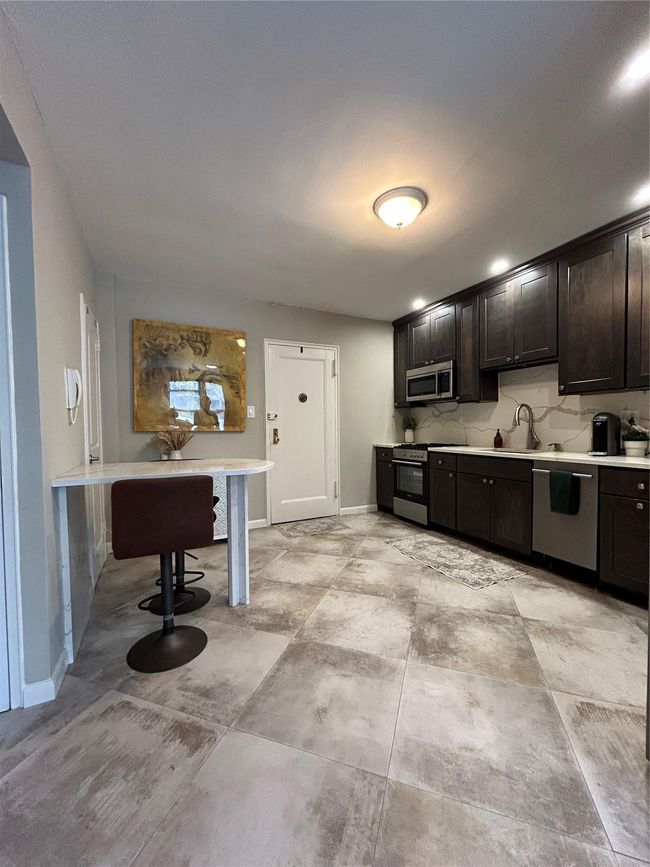Kitchen with dishwashing machine, stove, light countertops, and a sink | Image 6