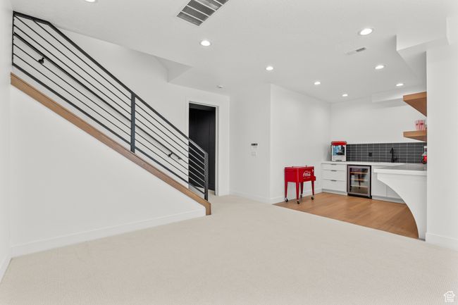 Kitchen featuring open shelves, recessed lighting, light colored carpet, decorative backsplash, and beverage cooler | Image 52